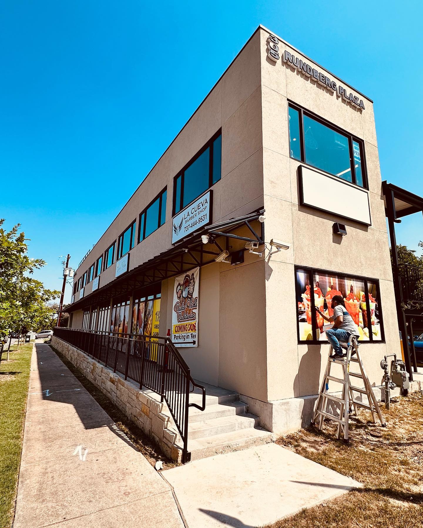 worker installing signage outside commercial building